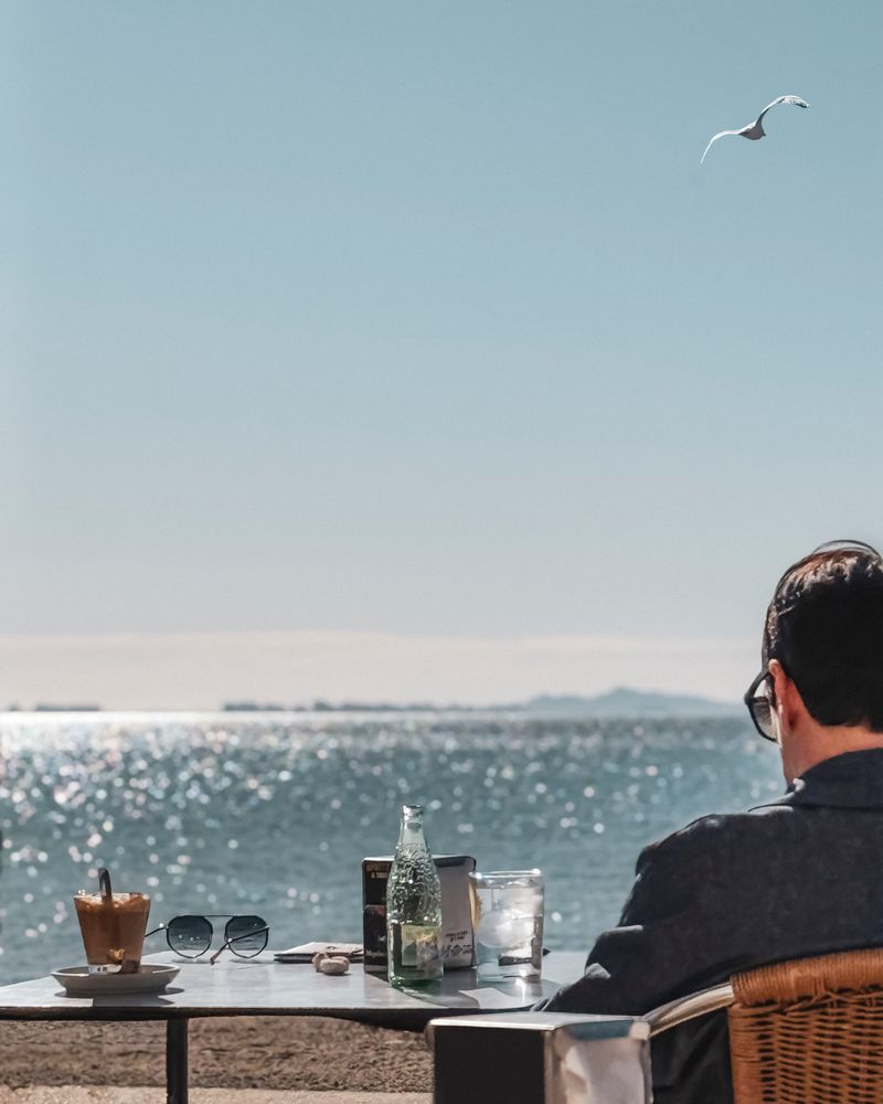 A seaside café table looking out over a calm, sunlit bay