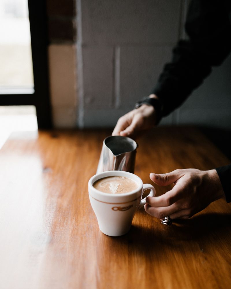 A barista pouring latte art into a cup