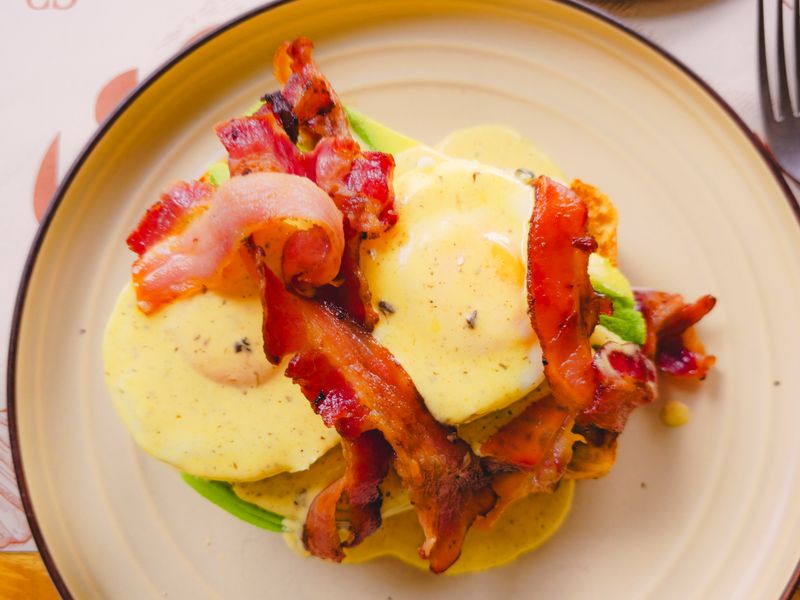 Eggs Benedict topped with crispy bacon