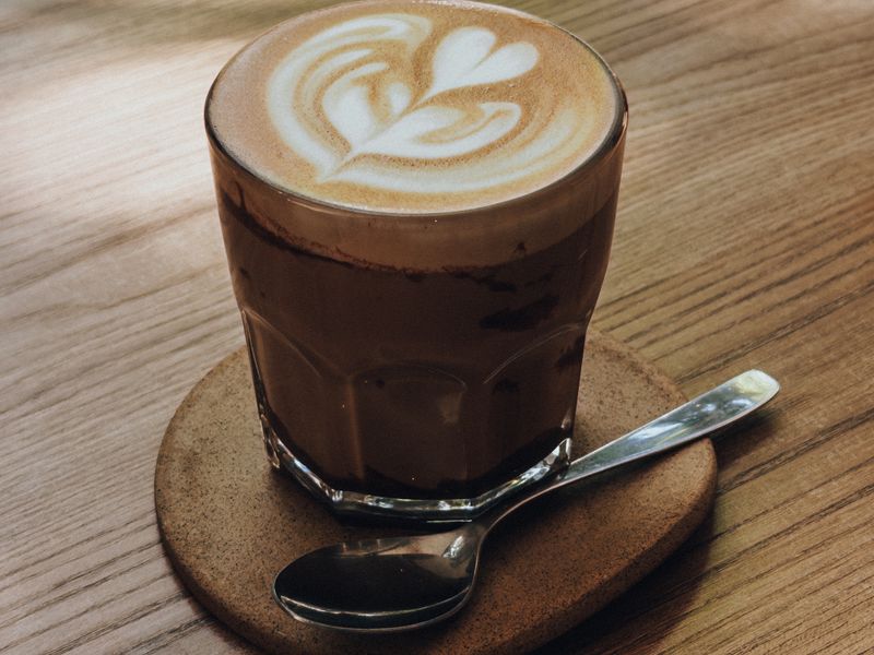 A flat white with latte art on a wooden table